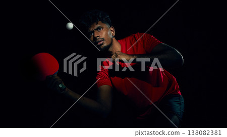 Table tennis player tracking ball during high speed rally in dark arena style lighting. Table tennis player tracking ball during high speed rally in dark arena style lighting. 138082381