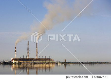 Thermal power station tall pipes with thick smoke reflected in lke water surface. Pollution of environment concept. Thermal power station tall pipes with thick smoke reflected in lke water surface. Pollution of environment concept. 138082460