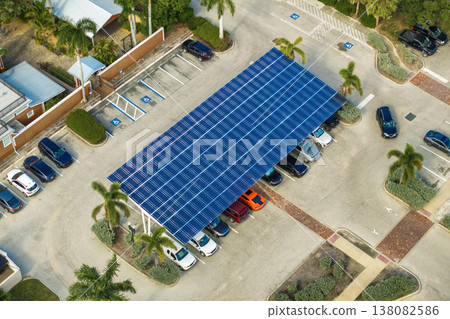 Solar power generation technology integrated in urban infrastructure. Photovoltaic panels installed as shade roof over parking lot with parked cars for effective production of clean energy. 138082586