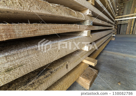 Neatly piled long stack of wooden boards inside attic room under construction. Neatly piled long stack of wooden boards inside attic room under construction. 138082786