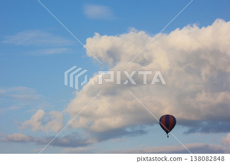 Lonely air baloon flying in front of white puffy clouds 138082848