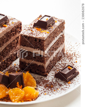 Traditional chocolate cocoa butter condensed milk cream cake with candies, oranges served on plate. 138082878