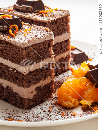 Traditional chocolate cocoa butter condensed milk cream cake with candies, oranges served on plate. 138082880