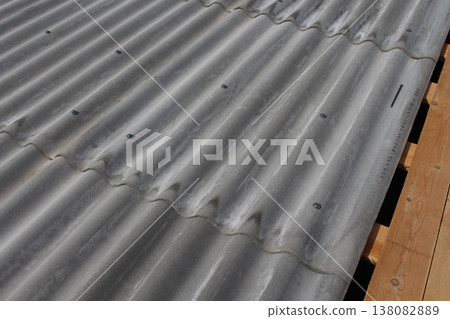 Traditional corrugated slate roof covering with diagonal wave pattern, metal bolts and exposed wooden beams at edge Traditional corrugated slate roof covering with diagonal wave pattern, metal bolts and exposed wooden beams at edge 138082889