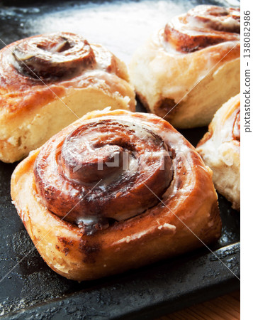 Freshly baked homemade cinnamon rolls with sweet cream cheese lying on oven pan. Freshly baked homemade cinnamon rolls with sweet cream cheese lying on oven pan. 138082986