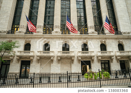American flags hang on the facade of the New York Stock Exchange building on Wall Street in Manhattan. Classical stone architecture and tall columns represent finance, business, and the United States American flags hang on the facade of the New York Stock Exchange building on Wall Street in Manhattan. Classical stone architecture and tall columns represent finance, business, and the United States 138083368