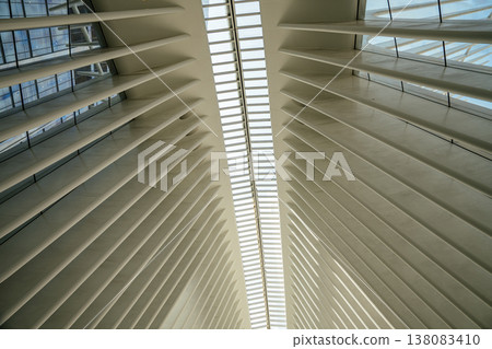 An angled perspective of the white architectural ribs and long glass skylight inside the Oculus in Lower Manhattan, New York City. The modern interior design highlights symmetry, geometry, and 138083410