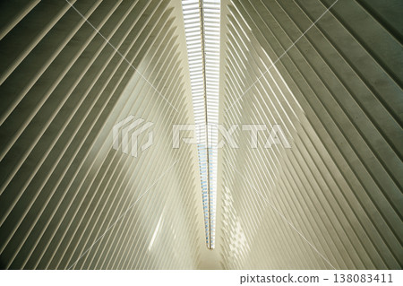 A close view of the white architectural ribs and skylight inside the Oculus in New York City. The repeating geometric lines create a futuristic and minimalist interior design. A close view of the white architectural ribs and skylight inside the Oculus in New York City. The repeating geometric lines create a futuristic and minimalist interior design. 138083411