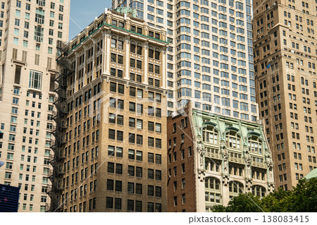 A historic brick building stands in front of modern glass skyscrapers in Manhattan, New York City. The dense urban architecture highlights the layered financial district skyline. A historic brick building stands in front of modern glass skyscrapers in Manhattan, New York City. The dense urban architecture highlights the layered financial district skyline. 138083415
