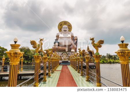 Giant laughing buddha statue at plai laem temple koh samui thailand with decorative bridge over water 138083475