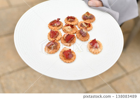 Hand holding plate of gourmet tartlet canapes with toppings assorted at a wedding Hand holding plate of gourmet tartlet canapes with toppings assorted at a wedding 138083489