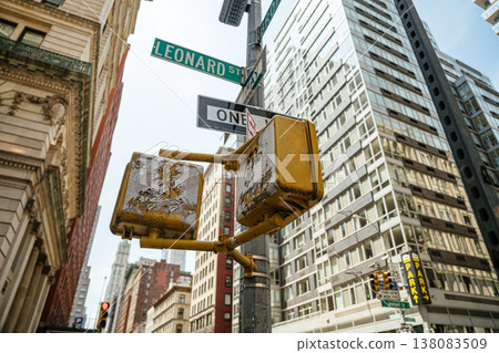 A Leonard Street and One Way sign stand against tall Manhattan buildings in New York City. The urban street scene highlights traffic signals and city infrastructure. A Leonard Street and One Way sign stand against tall Manhattan buildings in New York City. The urban street scene highlights traffic signals and city infrastructure. 138083509
