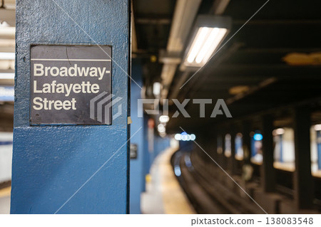 Close view of Broadway Lafayette Street subway station sign on blue steel column in Manhattan. Underground New York City metro platform with blurred railway tracks and urban transportation Close view of Broadway Lafayette Street subway station sign on blue steel column in Manhattan. Underground New York City metro platform with blurred railway tracks and urban transportation 138083548