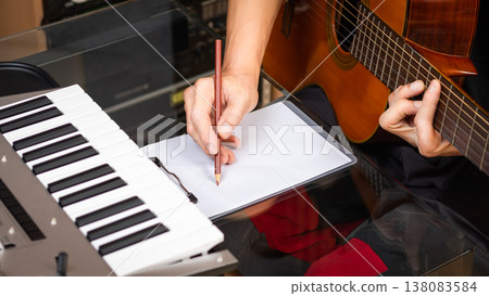 male musician writing a hit song by acoustic guitar in home studio. songwriting concept male musician writing a hit song by acoustic guitar in home studio. songwriting concept 138083584