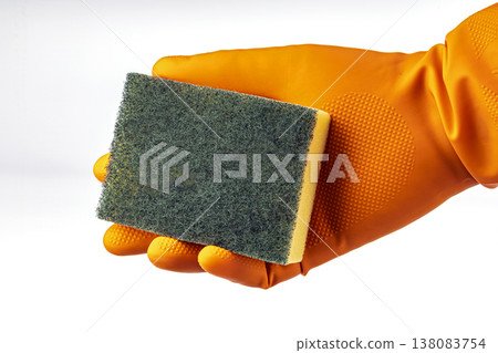Hand Wearing an Orange Protective Rubber Latex Glove Holding a Green and Yellow Dual-Sided Kitchen Scrubbing Sponge Isolated on Clean White Background 138083754