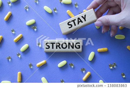 Stay Strong symbol. Concept word Stay Strong on wooden blocks. Beautiful purple background with pills. Doctor Hand. Medicine and Stay Strong concept. Copy space 138083863