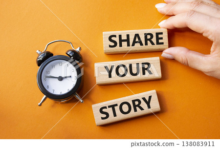 Share your story symbol. Wooden blocks with words Share your story. Businessman hand. Beautiful orange background with alarm clock. Business and Share your story concept. Copy space. 138083911