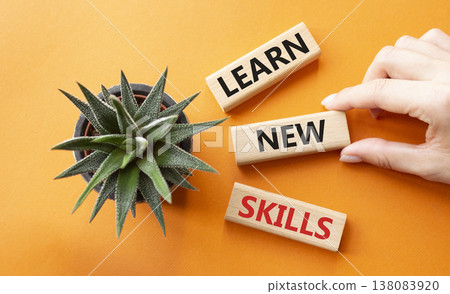 Learn new skills symbol. Concept words Learn new skills on wooden blocks. Beautiful orange background with succulent plant. Businessman hand. Business and Learn new skills concept. Copy space. 138083920