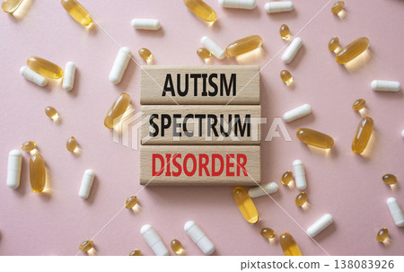 Autism Spectrum Disorder symbol. Concept word Autism Spectrum Disorder on wooden blocks. Beautiful pink background with pills. Medicine and Autism Spectrum Disorder concept. Copy space 138083926