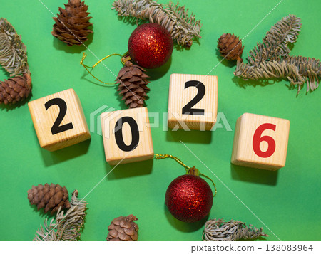 2026 New Year symbol. Wooden cubes with words 2026. Beautiful green background with Christmas balls and pine cones. Copy space. Business and 2026 happy new year concept 2026 New Year symbol. Wooden cubes with words 2026. Beautiful green background with Christmas balls and pine cones. Copy space. Business and 2026 happy new year concept 138083964