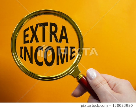 Extra Income symbol. Magnifying Glass with words Extra Income. Businessman hand. Beautiful orange background. Business and Extra Income concept. Copy space. Extra Income symbol. Magnifying Glass with words Extra Income. Businessman hand. Beautiful orange background. Business and Extra Income concept. Copy space. 138083980
