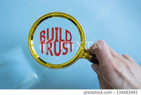 Build trust symbol. Magnifying Glass with Concept word Build trust. Beautiful blue background. Businessman hand. Business and Build trust concept. Copy space Build trust symbol. Magnifying Glass with Concept word Build trust. Beautiful blue background. Businessman hand. Business and Build trust concept. Copy space 138083991