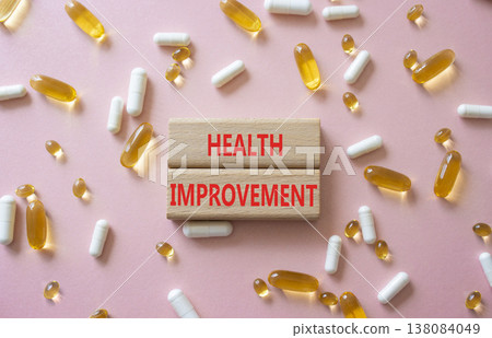 Health improvement symbol. Concept word Health improvement on wooden blocks. Beautiful pink background with pills. Medicine and Health improvement. Copy space 138084049