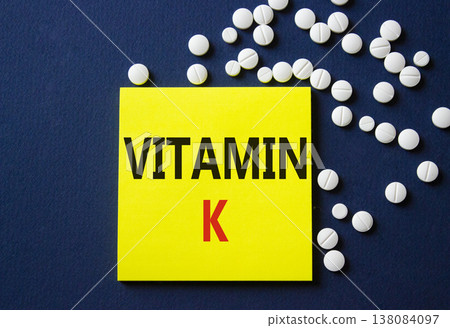 Vitamin K symbol. Concept word Vitamin K on yellow note. Beautiful deep blue background with pills. Medicine and Vitamin K concept. Copy space Vitamin K symbol. Concept word Vitamin K on yellow note. Beautiful deep blue background with pills. Medicine and Vitamin K concept. Copy space 138084097