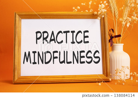 Mindfulness symbol. Concept words Practice Mindfulness on beautiful wooden picture frame. Beautiful orange background with flower vase. Medical and Psychology concept. Copy space. Mindfulness symbol. Concept words Practice Mindfulness on beautiful wooden picture frame. Beautiful orange background with flower vase. Medical and Psychology concept. Copy space. 138084114