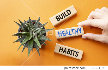 Healthy habits symbol. Concept word Build Healthy habits on wooden blocks. Doctor hand. Beautiful orange background with succulent plant. Healthy lifestyle and Healthy habits concept. Copy space Healthy habits symbol. Concept word Build Healthy habits on wooden blocks. Doctor hand. Beautiful orange background with succulent plant. Healthy lifestyle and Healthy habits concept. Copy space 138084198