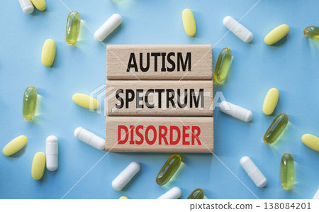 Autism Spectrum Disorder symbol. Concept word Autism Spectrum Disorder on wooden blocks. Beautiful blue background with pills. Medicine and Autism Spectrum Disorder concept. Copy space 138084201