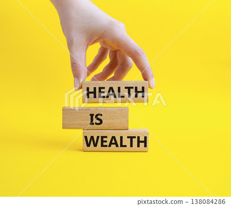 Health is Wealth symbol. Concept word Health is Wealth on wooden blocks. Businessman hand. Beautiful yellow background. Medicine and Health is Wealth concept. Copy space 138084286