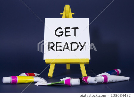 Get ready symbol. Wooden blocks with words Get ready. Beautiful deep blue background with paints and easel. Business and Get ready concept. Copy space. 138084482