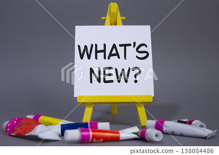 What is new symbol. Concept word What is new on wooden blocks. Beautiful grey background with paints and easel. Business and What is new concept. Copy space 138084486