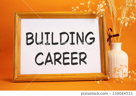 Building Career symbol. Concept words Building Career on beautiful wooden picture frame. Beautiful orange background with flower vase. Business and Building Career concept. Copy space. Building Career symbol. Concept words Building Career on beautiful wooden picture frame. Beautiful orange background with flower vase. Business and Building Career concept. Copy space. 138084511
