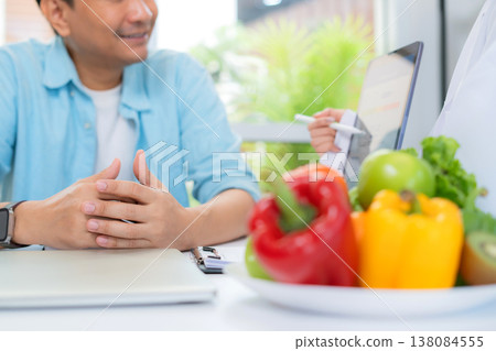 Asian woman nutritionist showing AI BMI calculator on tablet and explaining to man patient. 138084555
