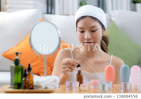 Beautiful young asian woman applying lotion herb on hands looking mirror at home. 138084556