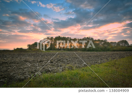 Clouds at sunset over a plowed rural field Clouds at sunset over a plowed rural field 138084909