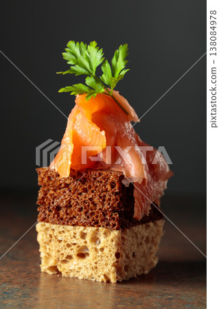 Open sandwich with smoked salmon garnished with fresh parsley against a dark background. 138084978