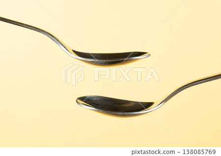 Two empty spoons on yellow background for design. Two empty spoons on yellow background for design. 138085769