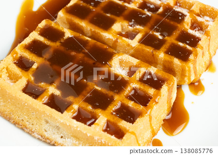 Delicious Belgian waffles topped with sweet caramel syrup close up. Delicious Belgian waffles topped with sweet caramel syrup close up. 138085776