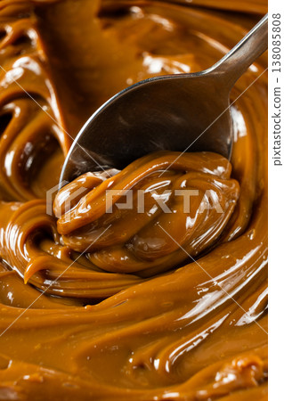 Dulce de leche on a spoon, thick boiled condensed milk Dulce de leche on a spoon, thick boiled condensed milk 138085808
