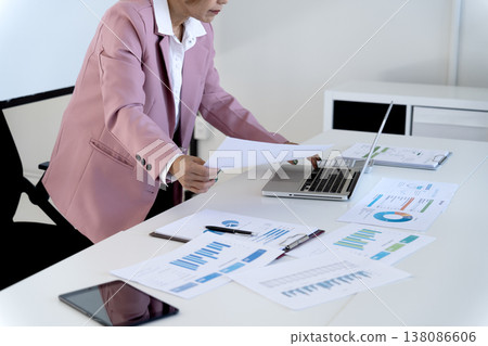 Senior female executive is standing looking at documents and computers 138086606