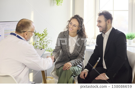Couple shaking hands with doctor during consultation in modern clinic office Couple shaking hands with doctor during consultation in modern clinic office 138086659