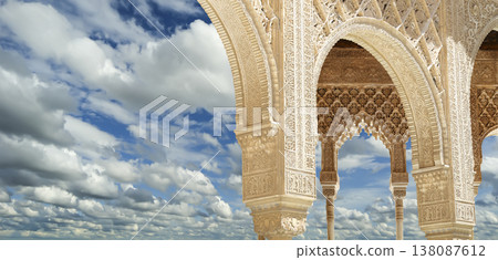 Arches in Islamic (Moorish) style (against the background of a beautiful sky with clouds) in Alhambra, Granada, Spain Arches in Islamic (Moorish) style (against the background of a beautiful sky with clouds) in Alhambra, Granada, Spain 138087612