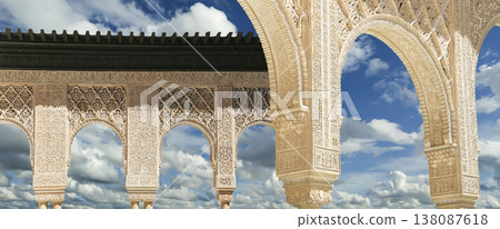 Arches in Islamic (Moorish) style (against the background of a beautiful sky with clouds) in Alhambra, Granada, Spain Arches in Islamic (Moorish) style (against the background of a beautiful sky with clouds) in Alhambra, Granada, Spain 138087618