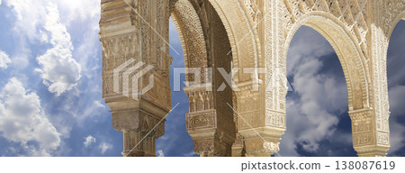 Arches in Islamic (Moorish) style (against the background of a beautiful sky with clouds) in Alhambra, Granada, Spain Arches in Islamic (Moorish) style (against the background of a beautiful sky with clouds) in Alhambra, Granada, Spain 138087619