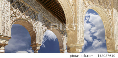Arches in Islamic (Moorish) style (against the background of a beautiful sky with clouds) in Alhambra, Granada, Spain Arches in Islamic (Moorish) style (against the background of a beautiful sky with clouds) in Alhambra, Granada, Spain 138087630