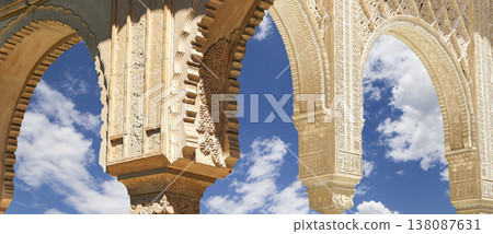 Arches in Islamic (Moorish) style (against the background of a beautiful sky with clouds) in Alhambra, Granada, Spain Arches in Islamic (Moorish) style (against the background of a beautiful sky with clouds) in Alhambra, Granada, Spain 138087631