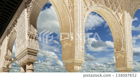 Arches in Islamic (Moorish) style (against the background of a beautiful sky with clouds) in Alhambra, Granada, Spain Arches in Islamic (Moorish) style (against the background of a beautiful sky with clouds) in Alhambra, Granada, Spain 138087652